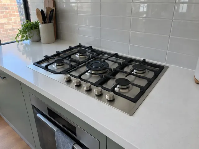 Built-in gas cooktop set into a white kitchen benchtop with tiled splashback in Cooks Hill