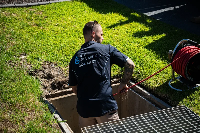 Plumber clearing a stormwater pit with a jetter hose